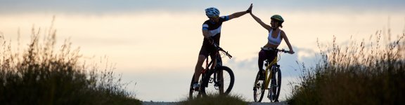 sporty-woman-man-riding-bicycles-having-fun-outside-silhouettes-sportsmen-highing-five-posing-road-sunset-time-non-urban-scene-1